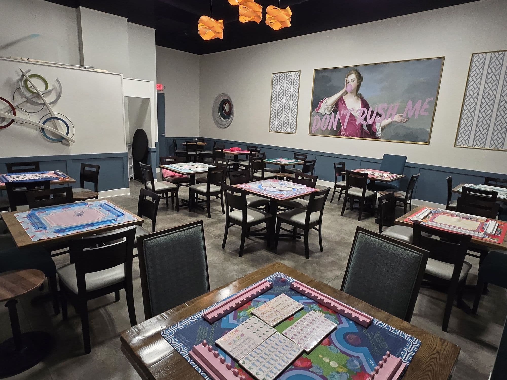 Wide view of the Sparrow & Palm play room with mahjong tables set and ready